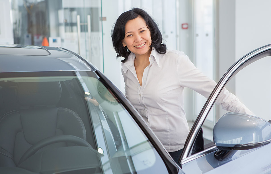 Smiling asian woman is buying a car at a dealership